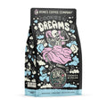 The front of a 12 ounce bag of Bones Coffee Company Cookies N’ Dreams coffee. Its flavor is cookies and vanilla ice cream, and it has a skeleton with a pillow and blanket holding a cookie and tub of ice cream on the art.